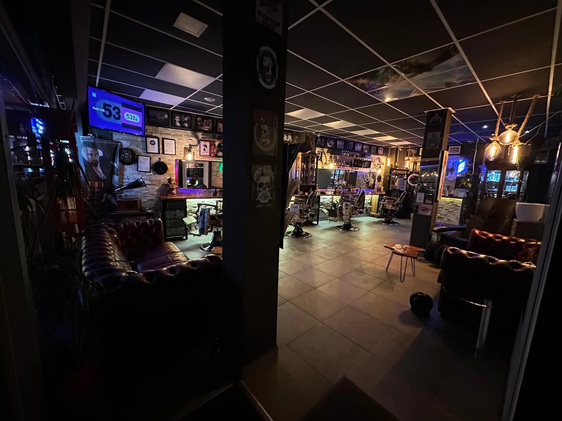 De sfeervol verlichte entree en barberstoelen bij Amro Style